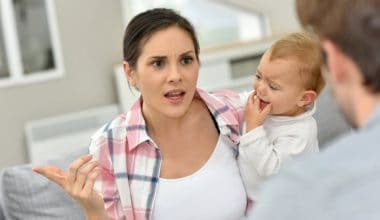 man and woman arguing in front of baby