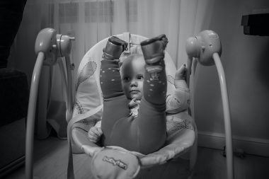 baby lifting her feet up while on a baby swing