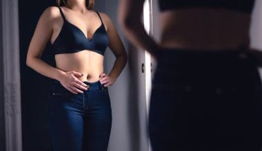 woman looking at her belly in the mirror