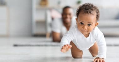 cute baby crawling in front of dad