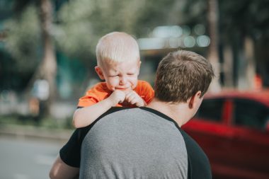 dad carrying crying baby boy