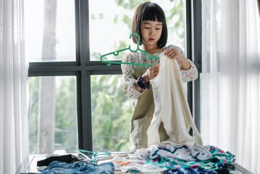 girl putting clothes on hanger