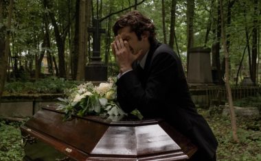 man crying beside a coffin