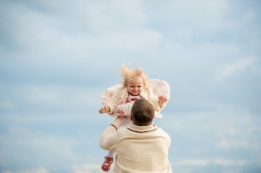 father carrying baby girl up in the air