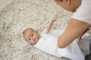 mom wrapping baby on a blanket
